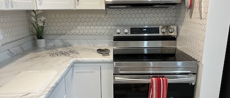 A kitchen with white cabinets, a microwave, and two ovens.