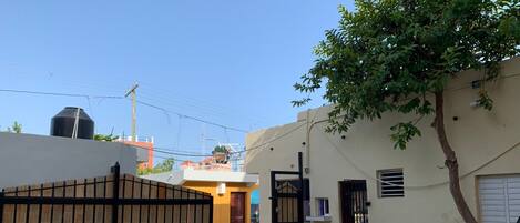 A residential area with a gated entrance, a tree, and a building with a tiled entrance.