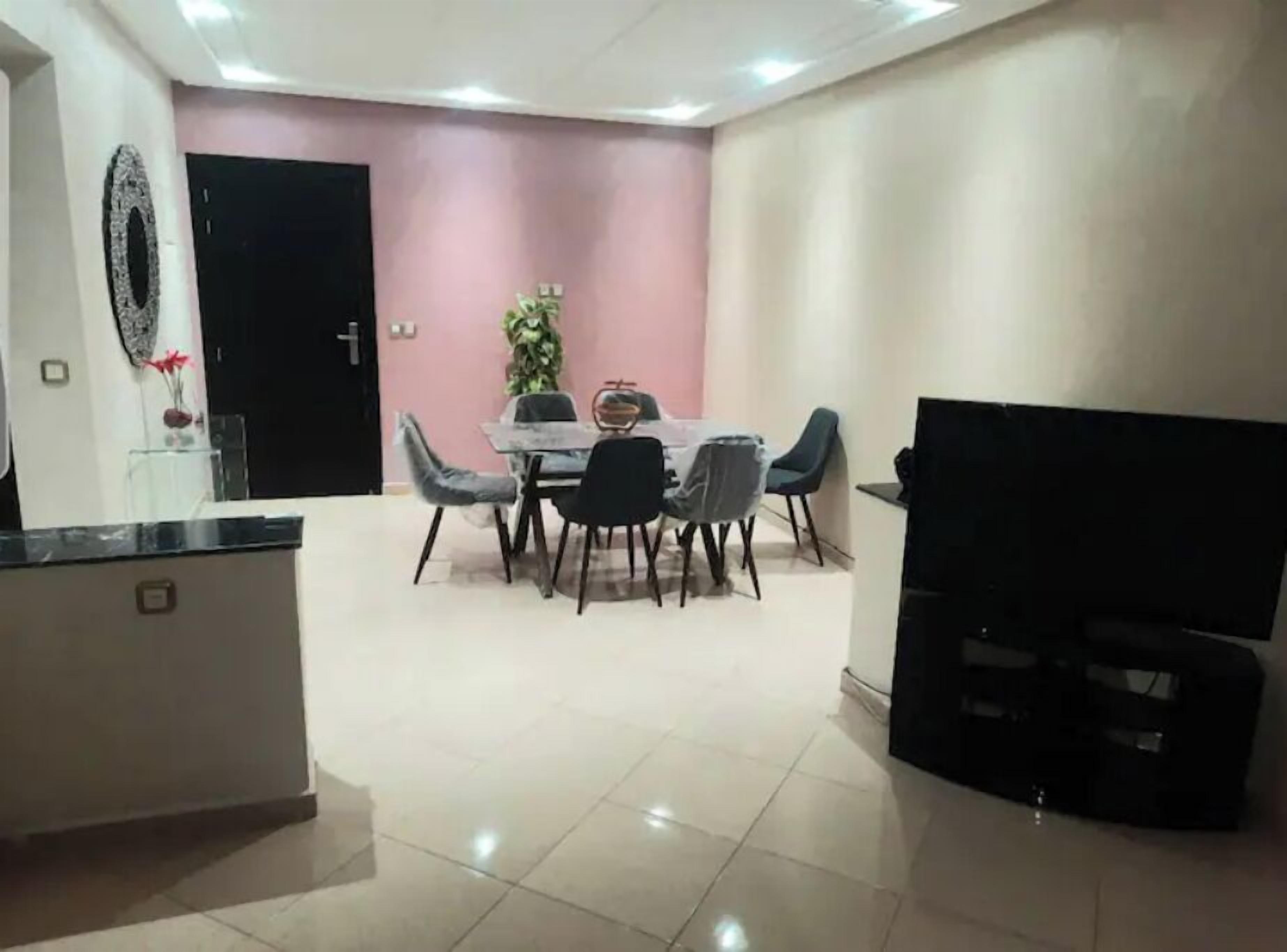 A dining area with a table and chairs, a TV, and a door.