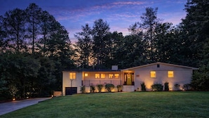 A two-story house with a front porch, a garage, and a well-maintained lawn. - Spacious 4BR Near Pinehurst | Fire Pit + Games (Southern Pines)