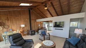 A spacious living room with a high ceiling, a fireplace, and a television.