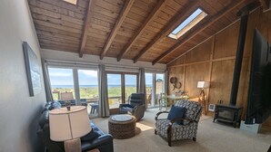 A cozy living room with a fireplace, comfortable seating, and large windows overlooking a scenic view.