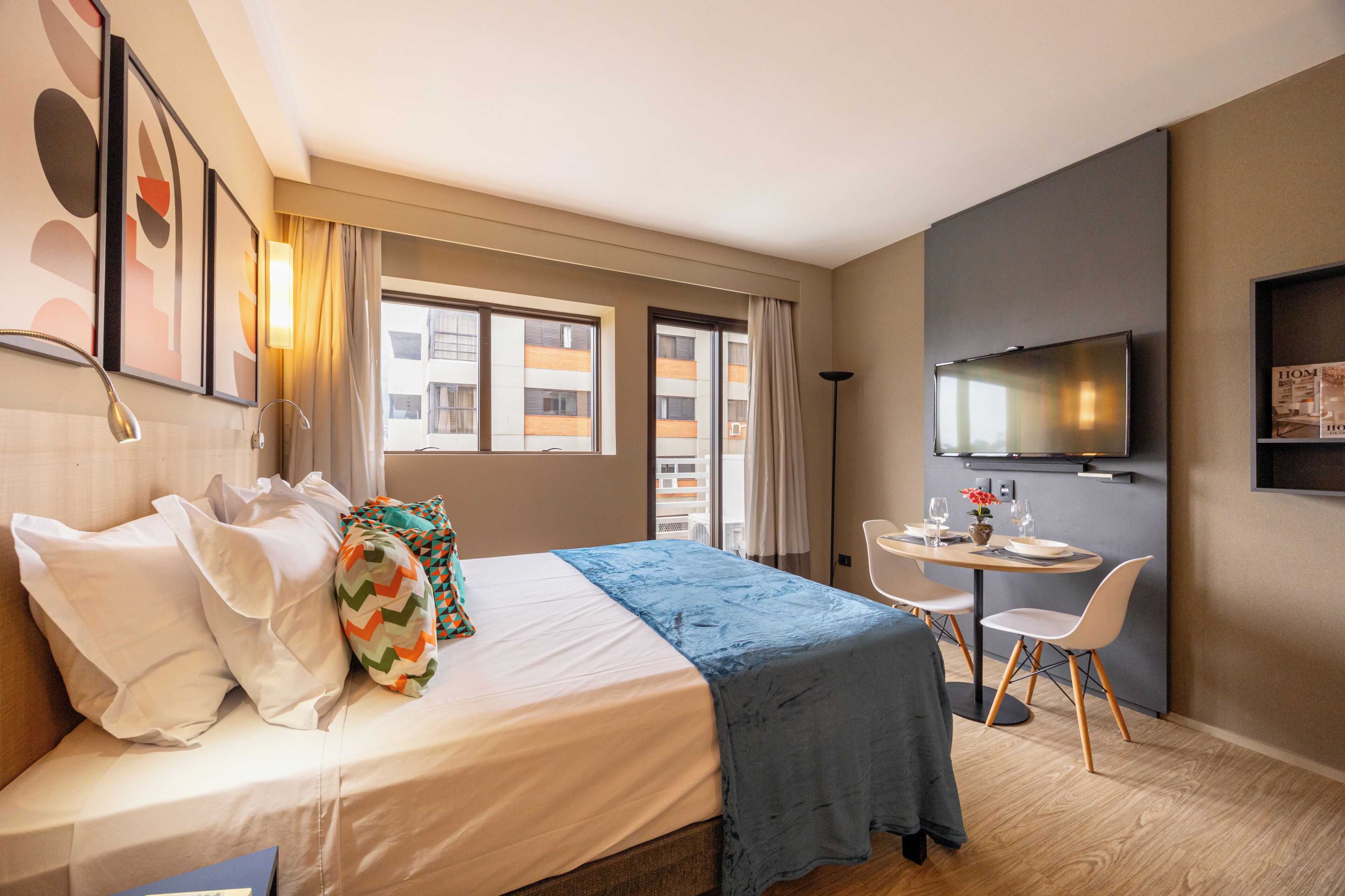 A hotel room with a bed, a desk, a chair, a television, and a window.