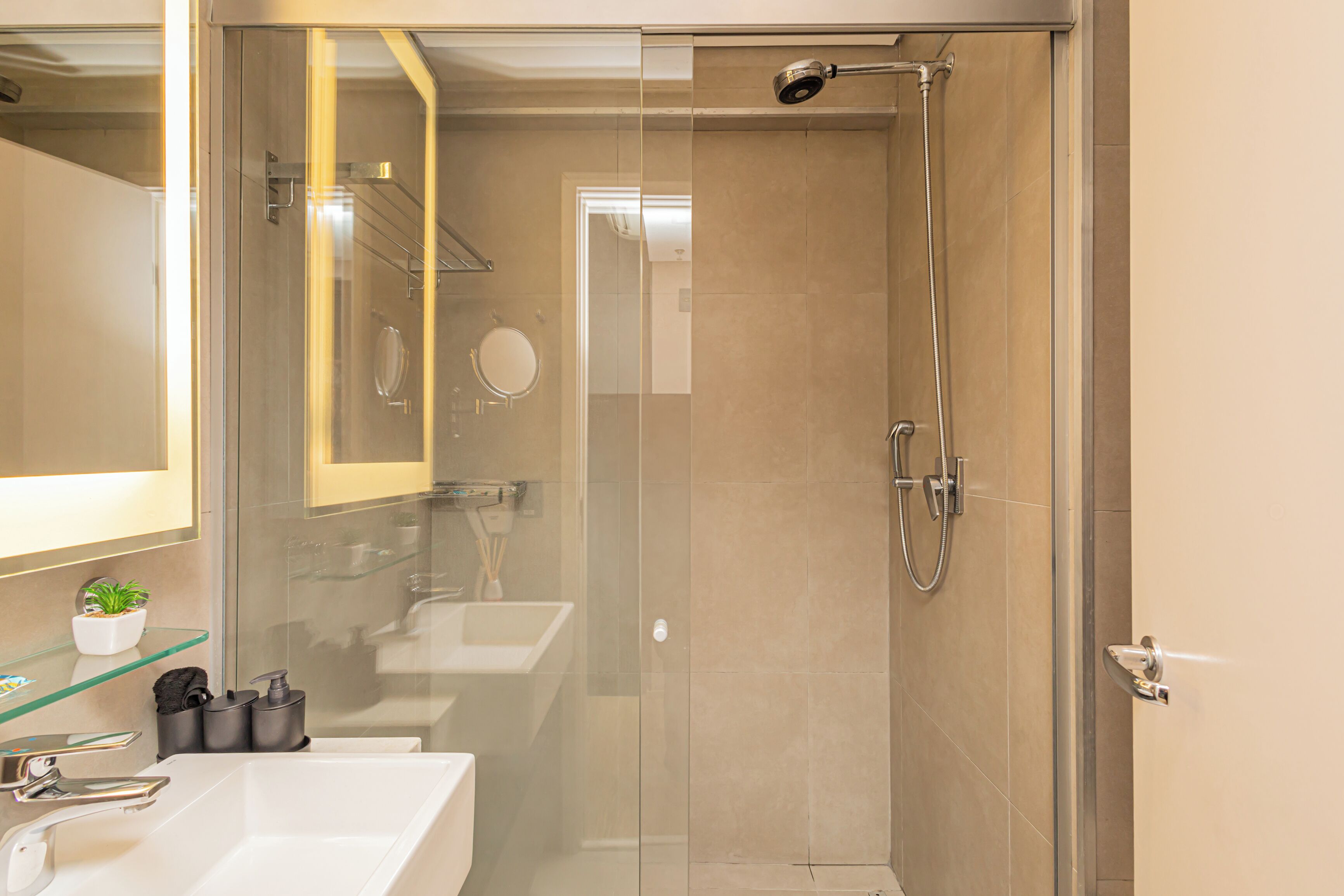 A modern bathroom with a glass-enclosed shower, a white sink, and a mirror.