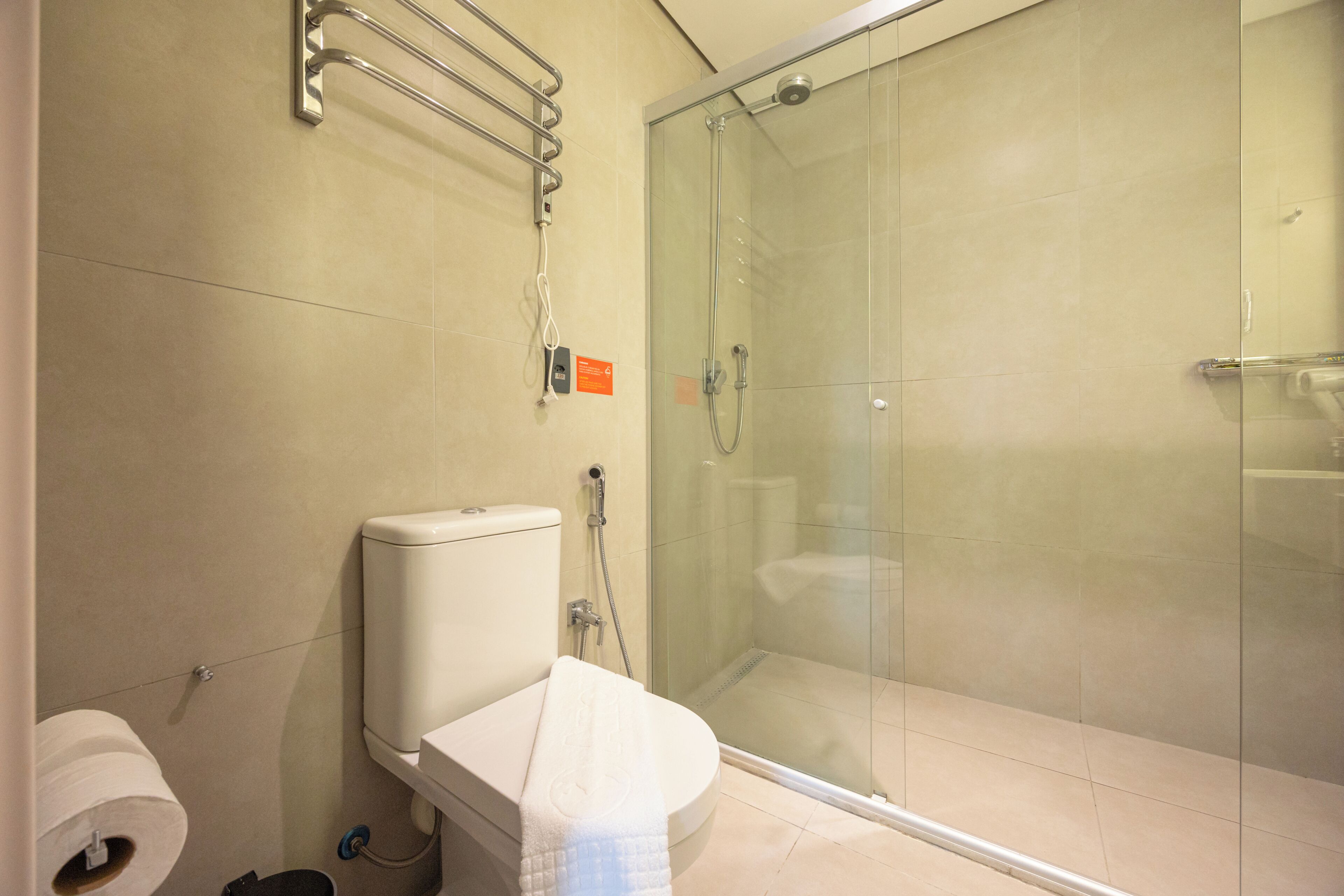 Une salle de bain moderne équipée de toilettes, d’une douche à parois de verre et d’un porte-serviettes.