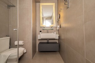 Un baño moderno con inodoro, lavamanos y espejo.