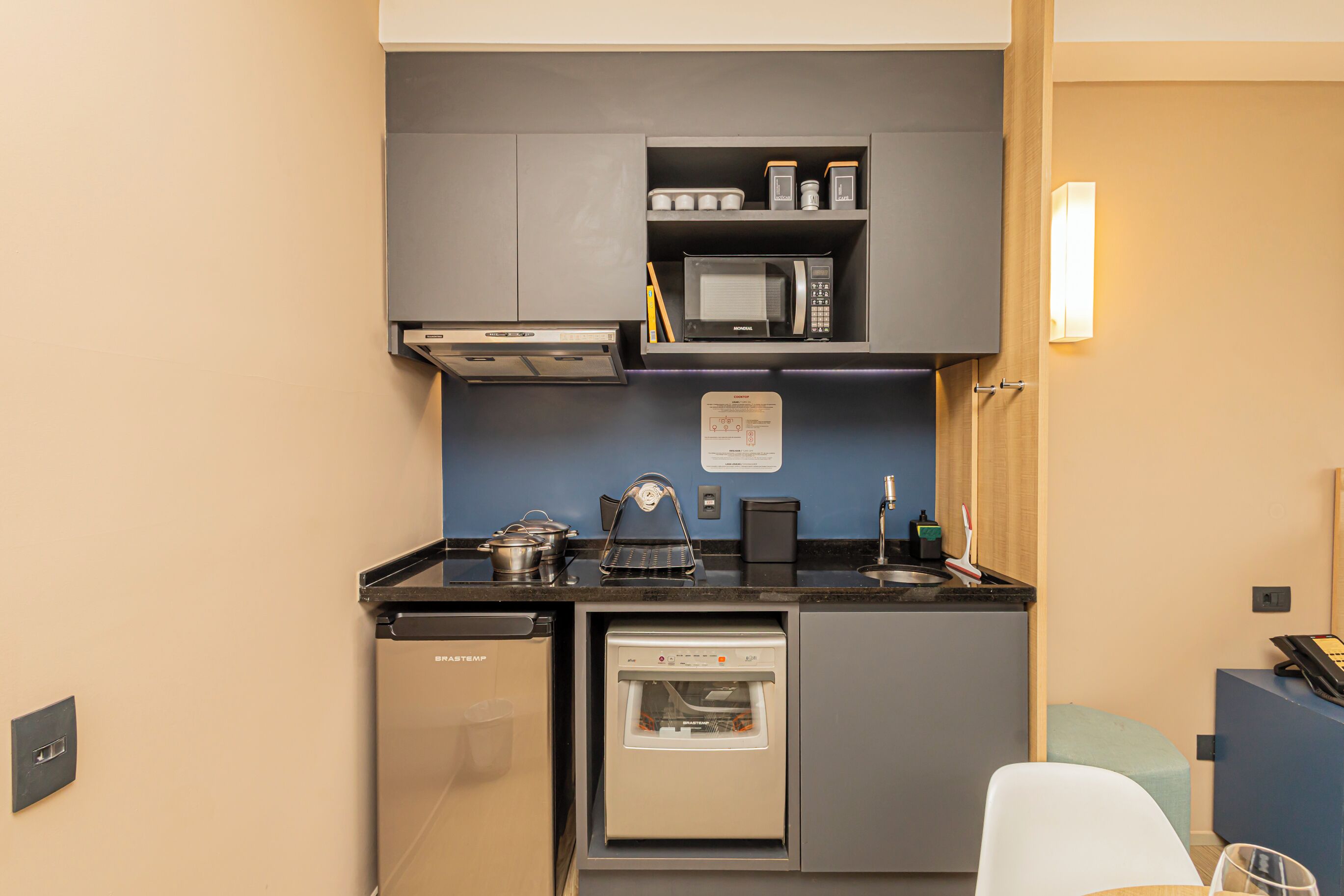 A compact kitchenette with a microwave, coffee maker, and a built-in dishwasher.
