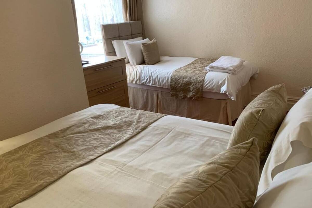 A hotel room with two beds, a desk, and a chair.