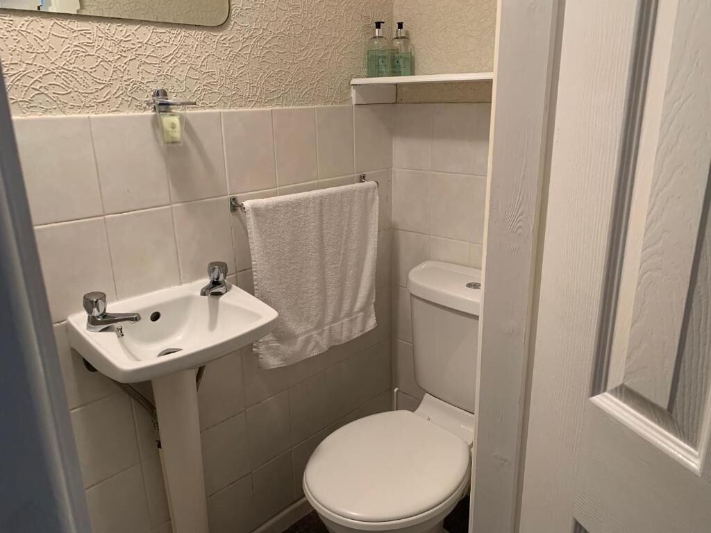 Un baño pequeño con lavamanos, inodoro y una toalla colgada en la pared.
