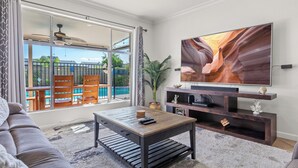 Un salon avec une grande télévision, une table basse en bois et un canapé.