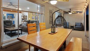 Un vaste espace de vie comprenant une table à manger en bois, des sièges confortables et un ventilateur de plafond.