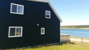 Une maison à deux étages, à l’extérieur sombre, avec des moulures blanches et de nombreuses fenêtres.