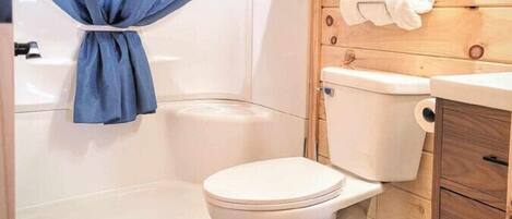 A bathroom with a shower curtain, toilet, and a towel rack.