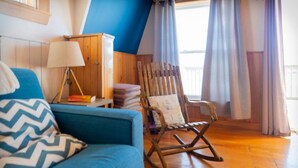 A cozy room with a blue sofa, a rocking chair, a lamp, and a wooden cabinet. - The most wanted place to stay in Cheticamp (Chéticamp)