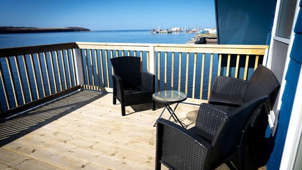 A wooden deck with two black wicker chairs and a small glass table. - The most wanted place to stay in Cheticamp (Chéticamp)