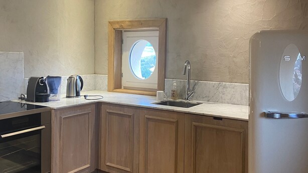 Una cocina moderna con armarios de madera, horno empotrado, refrigerador de acero inoxidable y ventana con vistas.