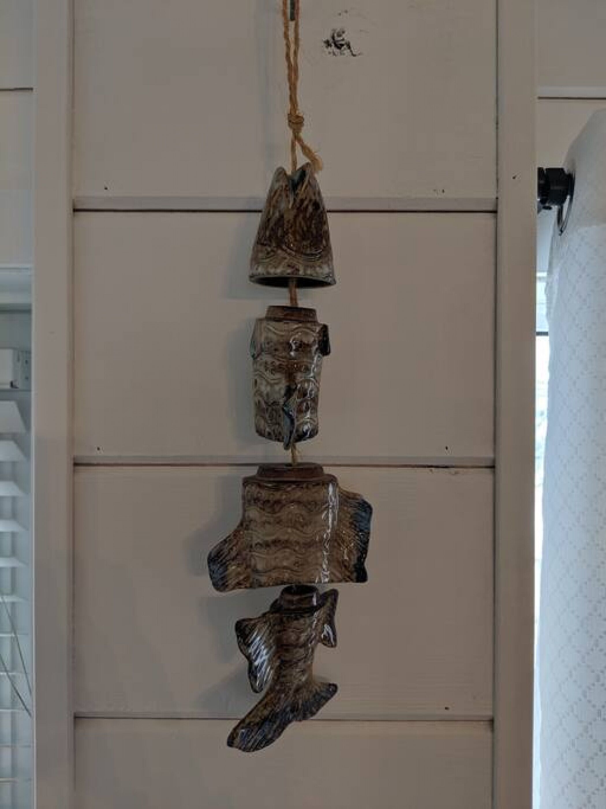 Un muro con tre sculture in legno appese.