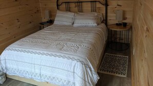 Una stanza in legno con un letto, due comodini e un tappeto.
