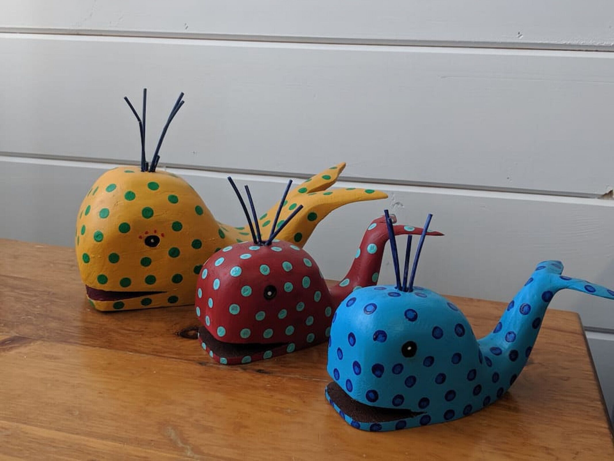 Trois bougies en forme de baleine posées sur une table en bois.