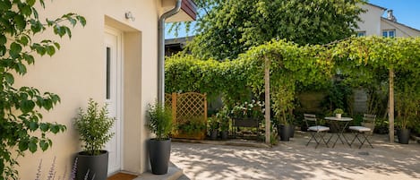 Uma casa com varanda coberta, plantas em vasos e móveis de exterior.