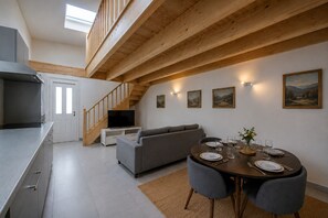 A modern interior with a kitchen, dining area, and living space, featuring a staircase and artwork on the walls.