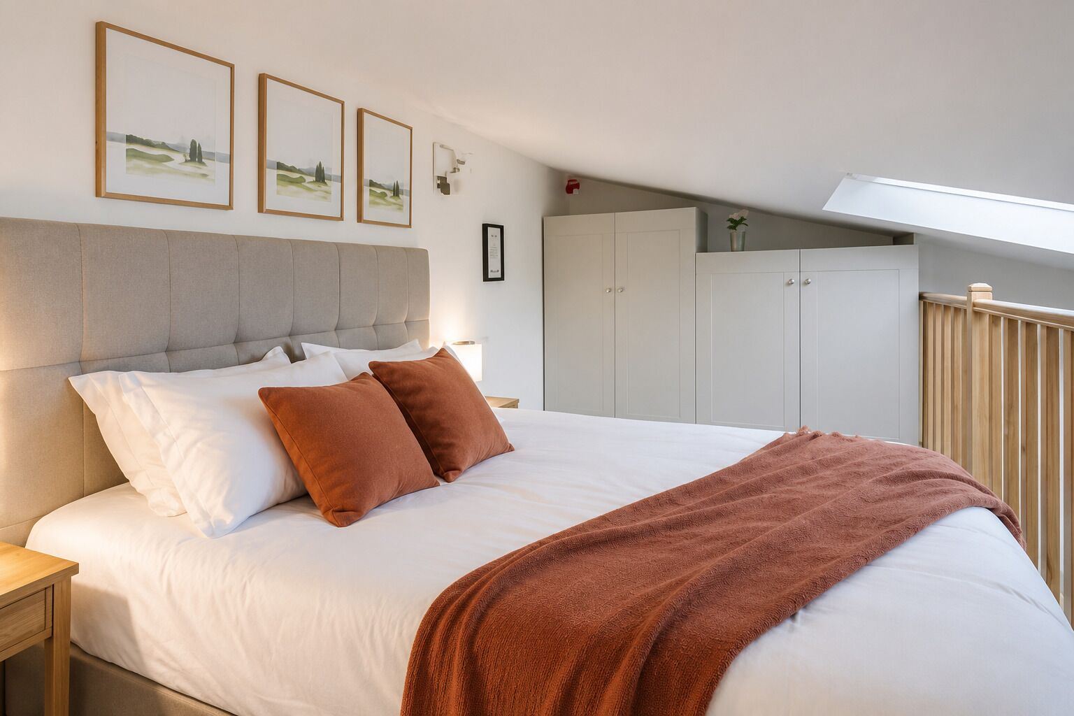 A bedroom with a large bed, a headboard, a nightstand, and a wardrobe.