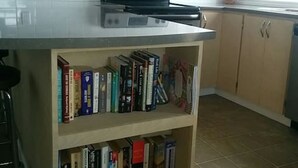 Une cuisine équipée d’une bibliothèque intégrée contenant des livres, d’une cuisinière et de placards.