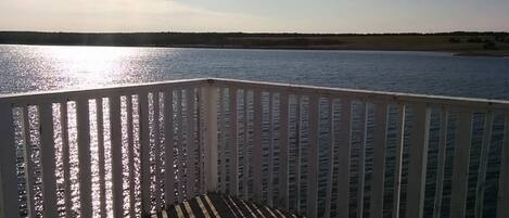 Een houten terras met een balustrade, met uitzicht op een rustig wateroppervlak.
