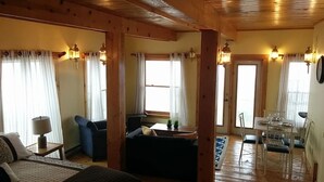 Um quarto acolhedor com uma cama, um sofá, uma mesa de jantar com cadeiras e uma janela com cortinas.