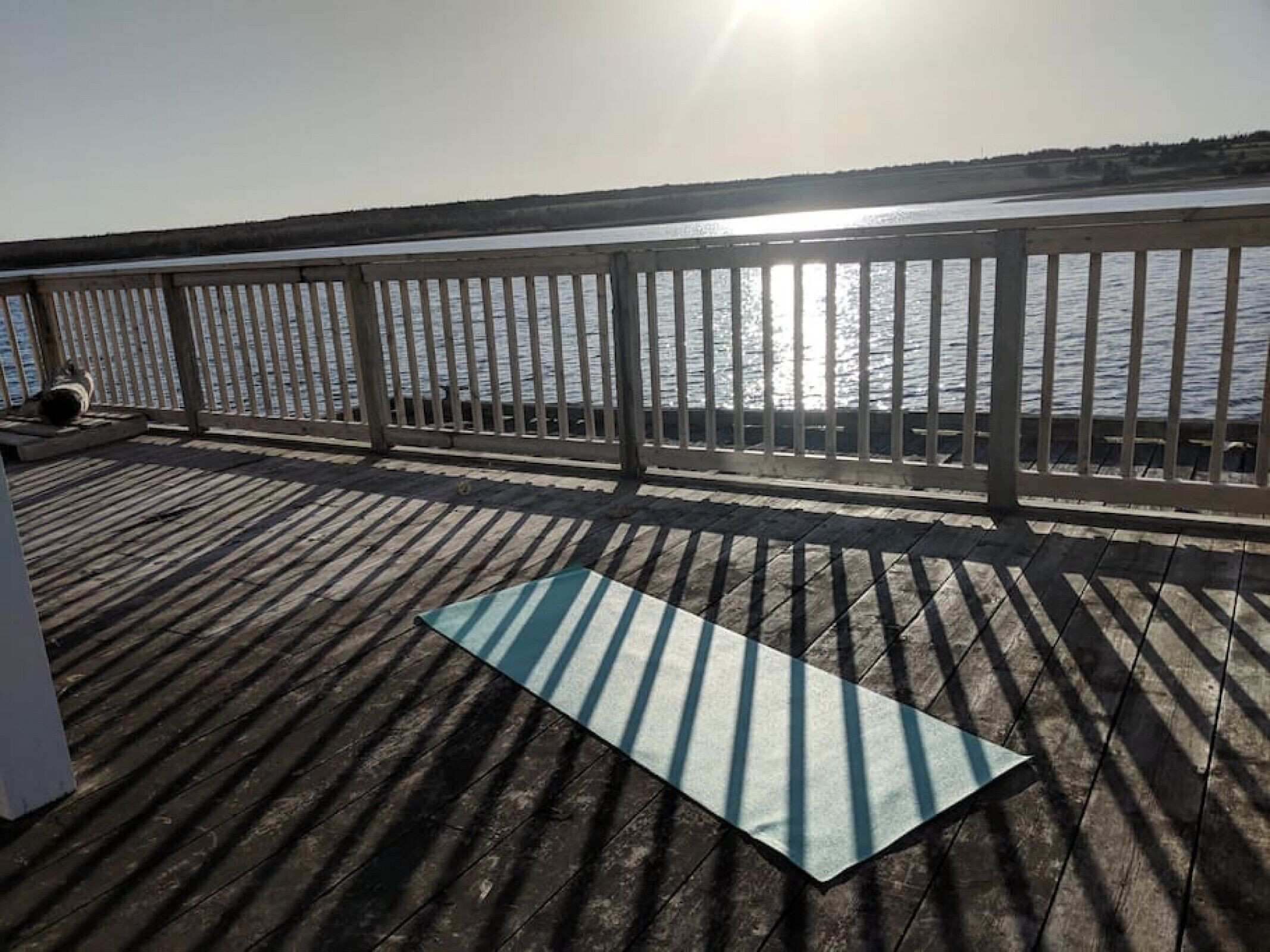 Una terraza de madera con barandilla de metal que da a un cuerpo de agua.