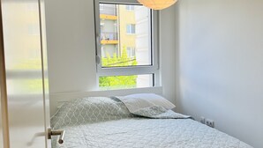 Un dormitorio con cama, ventana y lámpara colgante.