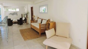 Un vaste espace de vie comprenant un canapé en bois, un lit en bois et une table à manger avec des chaises.