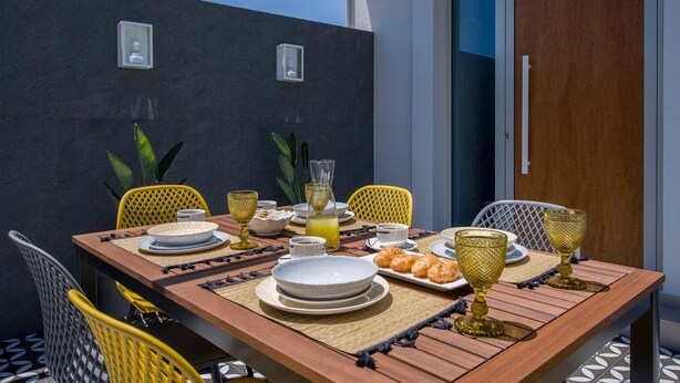 A dining table set outdoors with plates, glasses, and a pitcher of orange juice. - Casa Di Camomilla (Platanias)