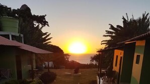 A pathway leading to a building with a sunset in the background. - Pousada Maramar (Fernando de Noronha)