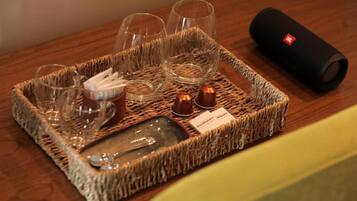 A tray with glasses, a bottle, and a small dish on a woven mat, accompanied by a black cylindrical object.