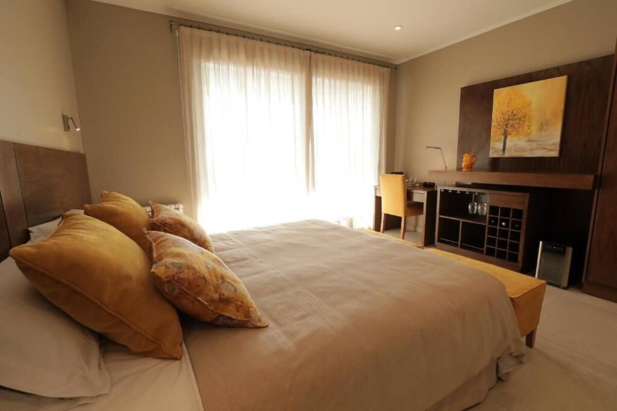 A spacious bedroom with a large bed, a desk, and a fireplace.