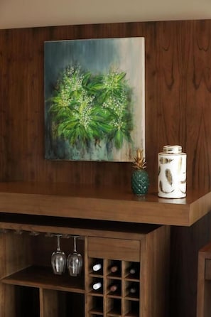 A wooden shelf with a painting of green foliage, a pineapple, and a patterned container. - Gaia Lodge (Tupungato)