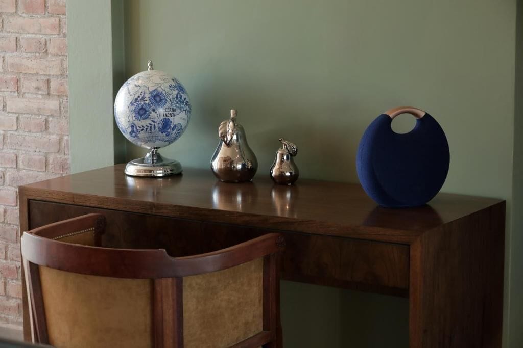 Un escritorio de madera con un globo terr áqueo, dos jarrones metálicos y un cuenco azul.