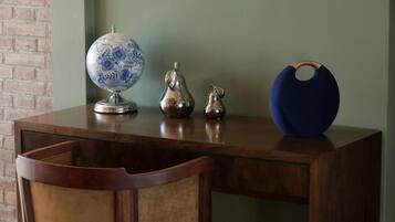 Un escritorio de madera con un globo terráqueo, dos jarrones metálicos y un cuenco azul.