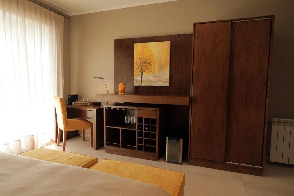 Hotelkamer met een bed, een bureau, een stoel, een kledingkast, een schilderij en een radiator.