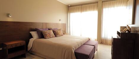 A bedroom with a bed, nightstand, bench, and a dresser.
