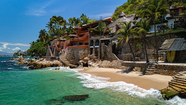 A coastal hotel with a beach, palm trees, and ocean views.