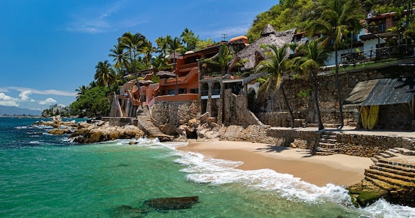 A coastal hotel with a beach, palm trees, and ocean views.
