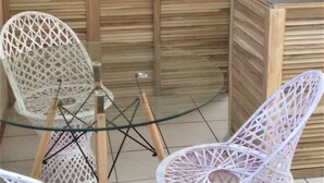 Una habitación con dos sillas de mimbre, una mesa de vidrio y un separador de madera.