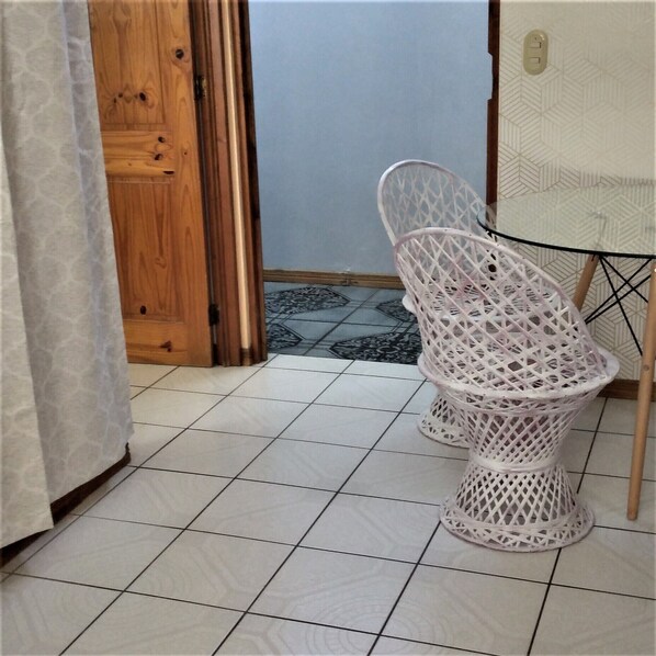 A bathroom with a white toilet, a wooden door, and a patterned floor.
