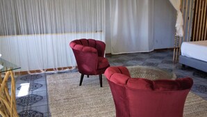 Una habitación con una cama, un sillón rojo y una mesa de vidrio.
