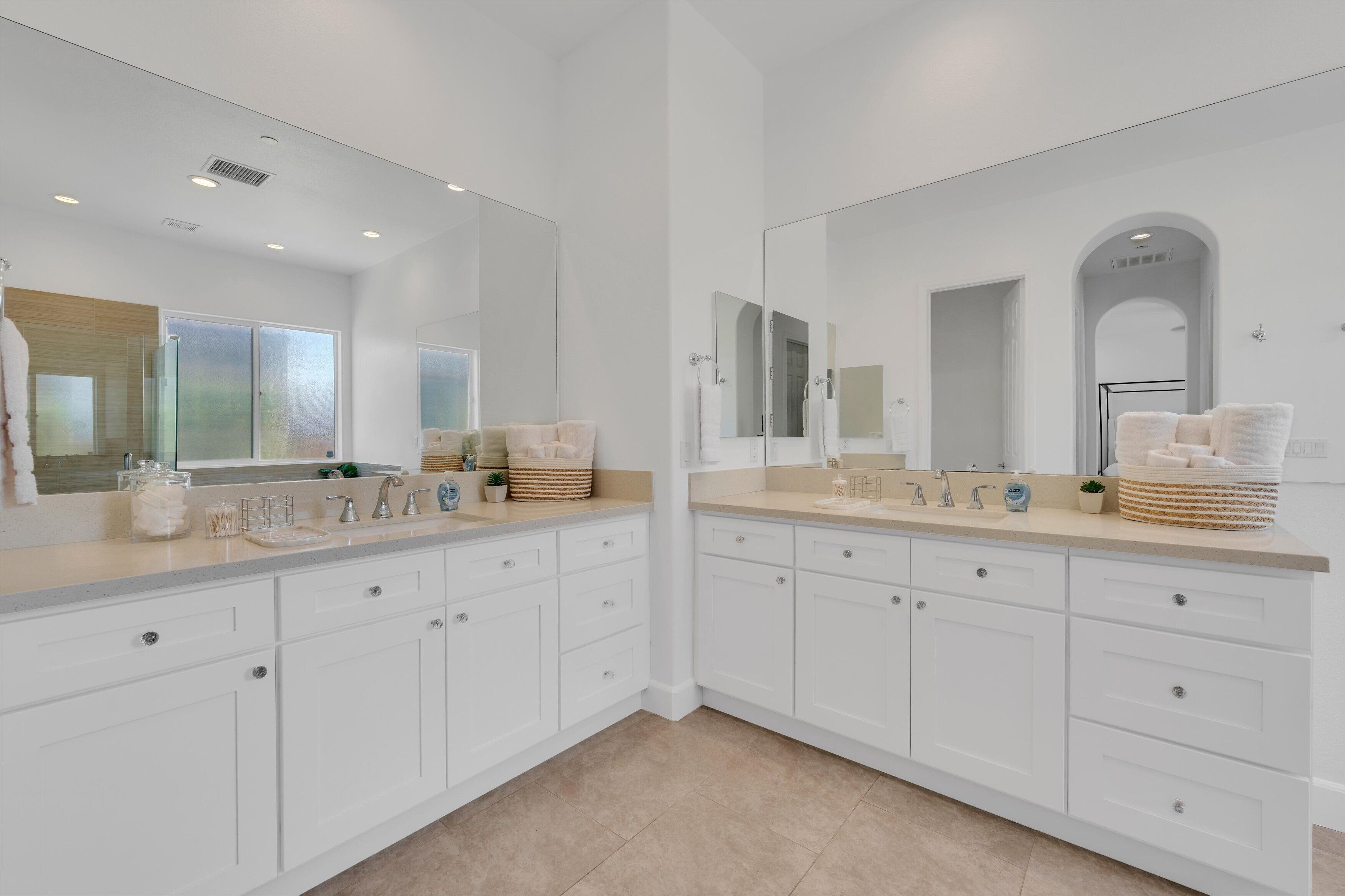 A modern bathroom with two sinks, large mirrors, and white cabinetry.