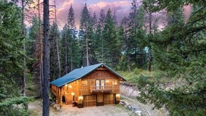 Una cabaña de madera con balcón, rodeada de un bosque frondoso.