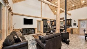 Un amplio salón con chimenea, sofás de cuero y un televisor de pantalla plana.