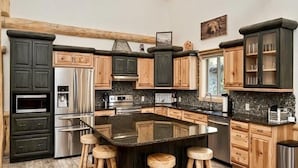 Una cocina moderna con armarios de madera oscura, electrodomésticos de acero inoxidable y una isla central con taburetes.